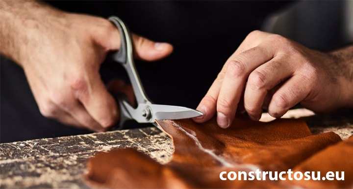 Mâini de bărbat și o foarfecă pentru piele